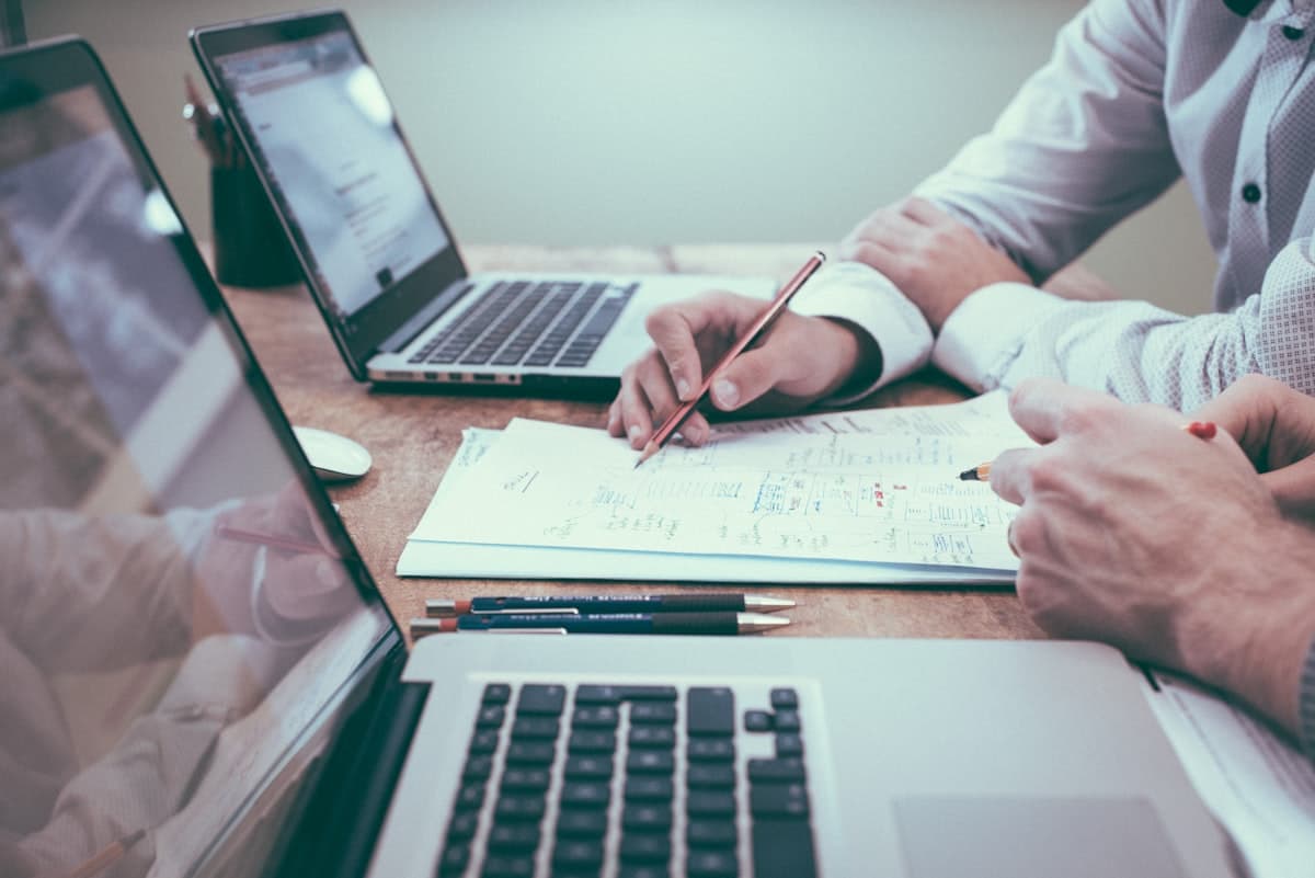Due professionisti analizzano documenti e dati su laptop durante una consulenza informatica
